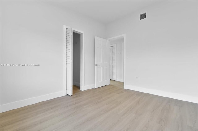 spare room with baseboards, visible vents, and wood finished floors