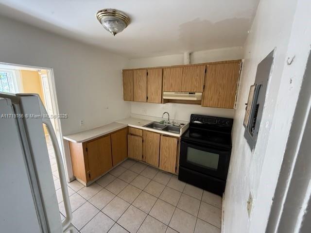 kitchen featuring sink, black electric range, refrigerator, and light tile patterned flooring