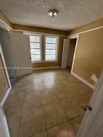 unfurnished bedroom with light tile patterned flooring, a closet, and a textured ceiling