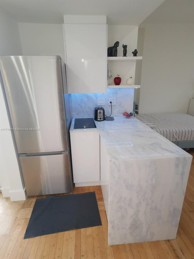 kitchen with kitchen peninsula, stainless steel fridge, and light hardwood / wood-style floors