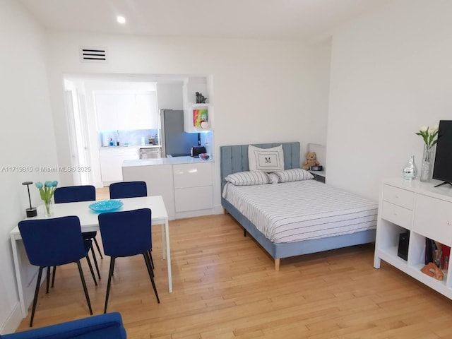 bedroom featuring stainless steel fridge and light wood-type flooring