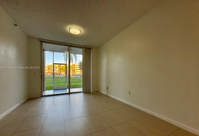 empty room with light tile patterned floors, a textured ceiling, and expansive windows