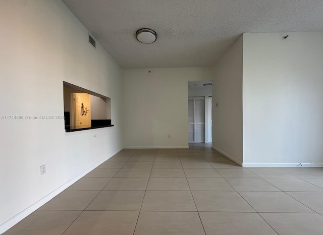 unfurnished room featuring light tile patterned flooring and a textured ceiling