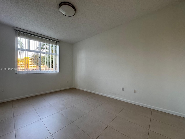 empty room with light tile patterned floors and a textured ceiling