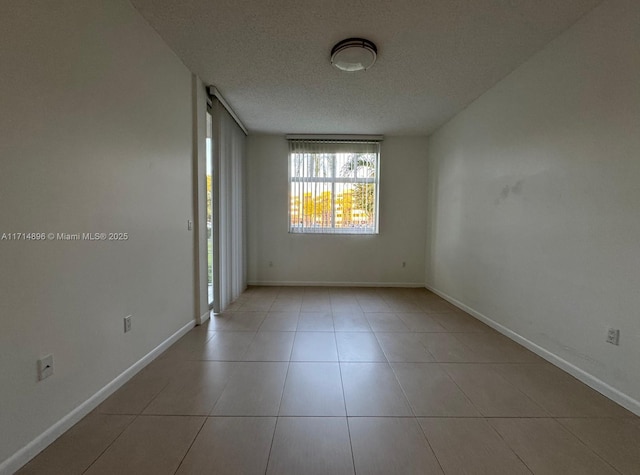 empty room with light tile patterned floors and a textured ceiling