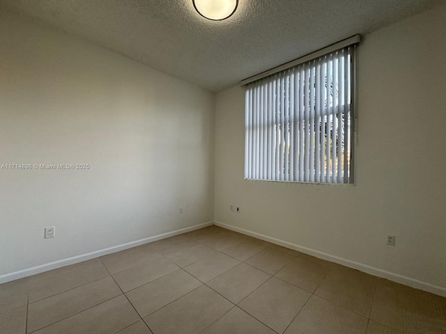 tiled empty room with a textured ceiling