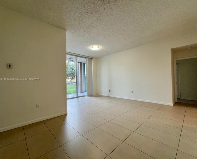 spare room with a textured ceiling and light tile patterned flooring