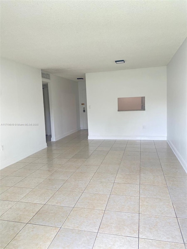 empty room with light tile patterned floors and a textured ceiling