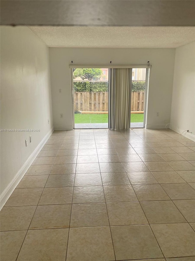 unfurnished room with a textured ceiling and light tile patterned flooring