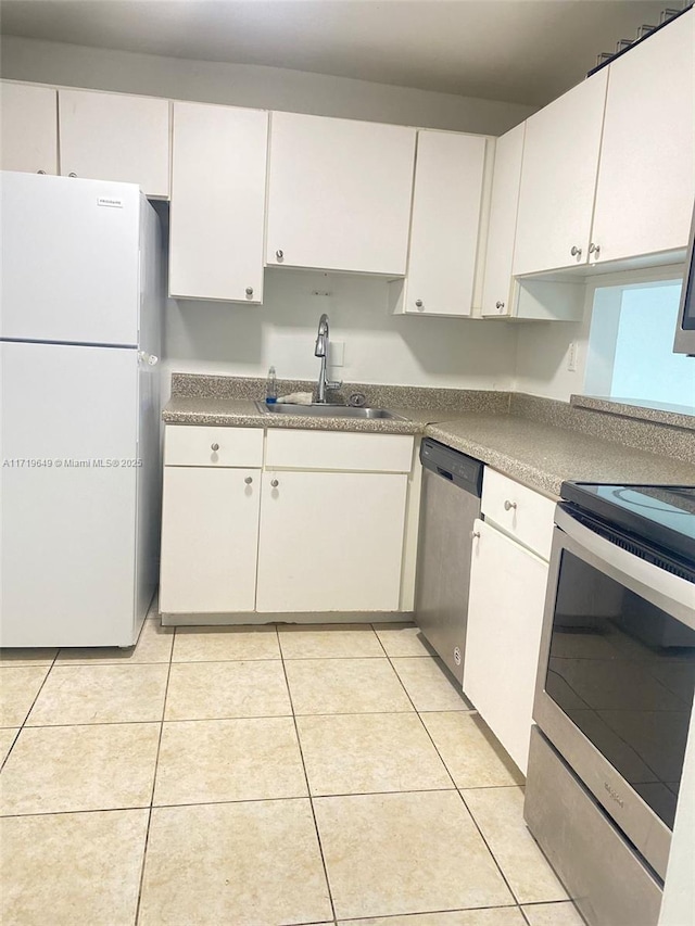 kitchen featuring sink, white cabinets, light tile patterned floors, and appliances with stainless steel finishes