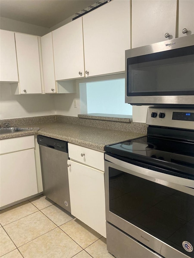 kitchen with light tile patterned floors, white cabinetry, and appliances with stainless steel finishes