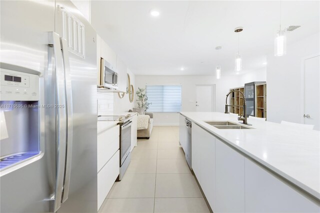 kitchen featuring sink, white cabinetry, stainless steel appliances, and hanging light fixtures