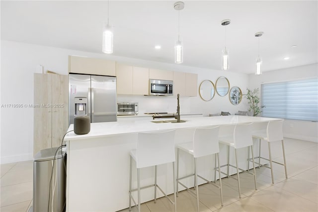 kitchen featuring pendant lighting, light tile patterned floors, stainless steel appliances, and an island with sink