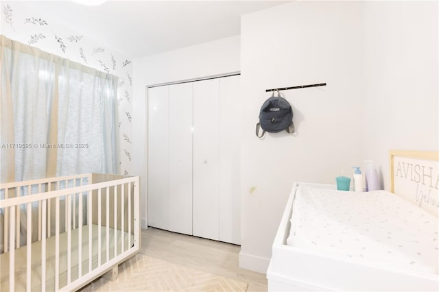 bedroom featuring a closet, a nursery area, and light hardwood / wood-style floors