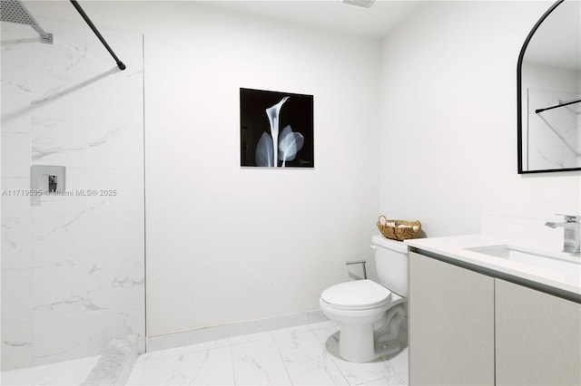 bathroom with tiled shower, vanity, and toilet