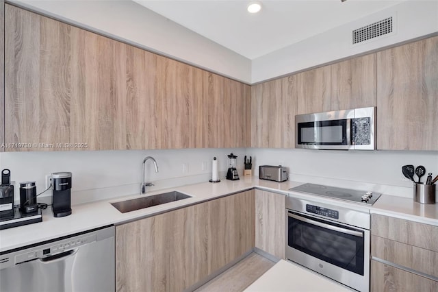 kitchen featuring light brown cabinetry, sink, and appliances with stainless steel finishes