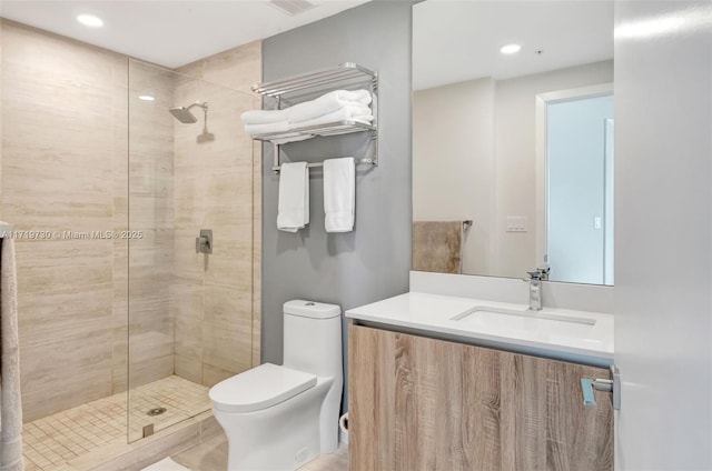 bathroom featuring a tile shower, vanity, and toilet