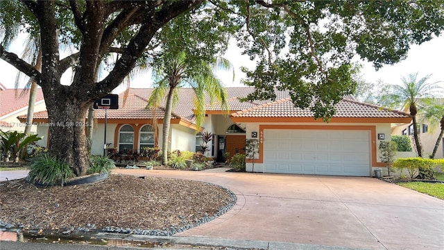 view of front of house with stucco siding, concrete driveway, an attached garage, and a tile roof