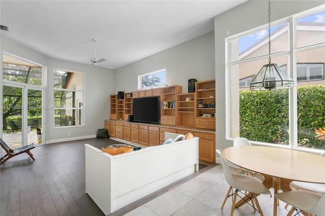 living area featuring a ceiling fan, visible vents, light wood finished floors, baseboards, and a textured ceiling