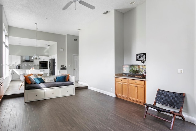 sitting room featuring a towering ceiling, dark hardwood / wood-style flooring, a textured ceiling, and ceiling fan