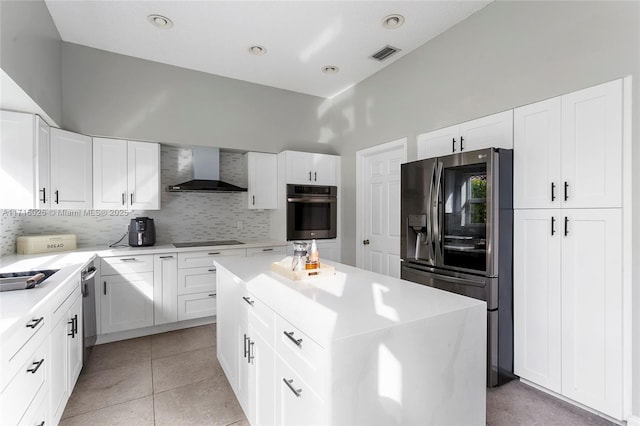 kitchen featuring stainless steel appliances, white cabinetry, and wall chimney exhaust hood