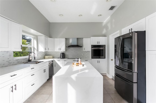 kitchen with a center island, stainless steel appliances, wall chimney range hood, white cabinets, and sink