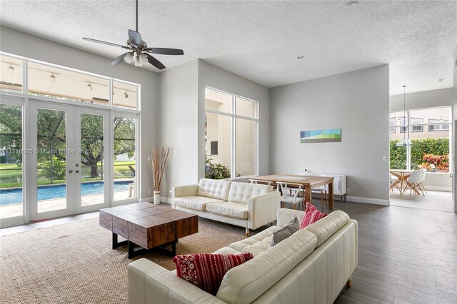 living room with french doors, a textured ceiling, ceiling fan, and wood-type flooring