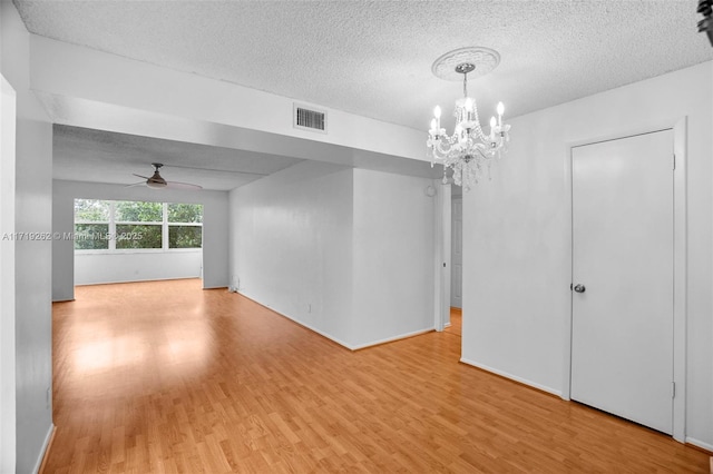 unfurnished room featuring a textured ceiling, ceiling fan with notable chandelier, and light hardwood / wood-style flooring