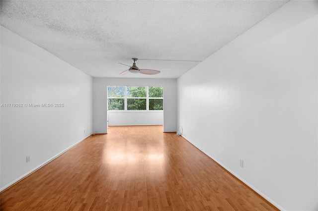 empty room featuring a textured ceiling, light wood-type flooring, and ceiling fan