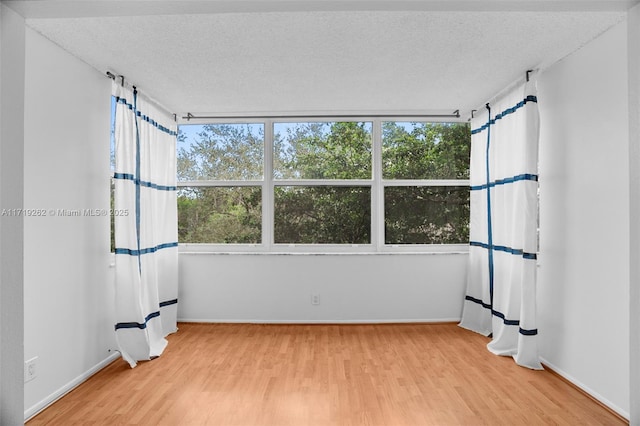 unfurnished room featuring hardwood / wood-style floors and a textured ceiling