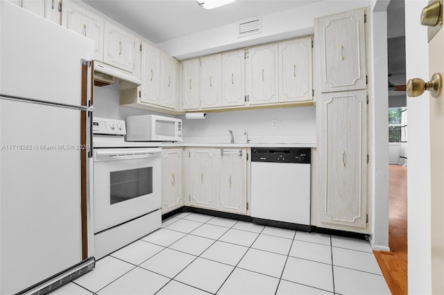 kitchen with white cabinets, sink, light tile patterned floors, and white appliances