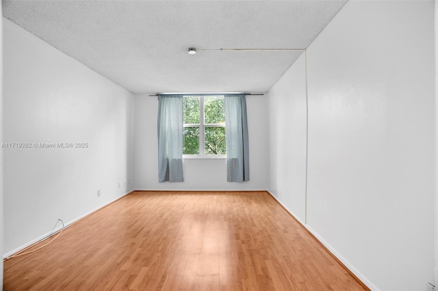 spare room with light wood-type flooring and a textured ceiling