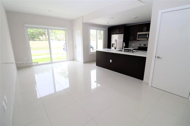 kitchen featuring tasteful backsplash, sink, light tile patterned flooring, and appliances with stainless steel finishes