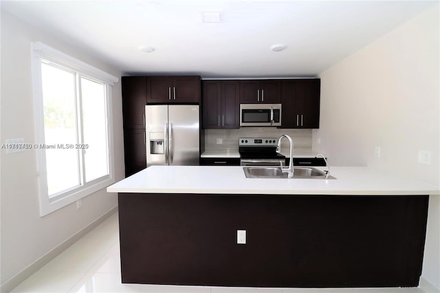 kitchen featuring sink, stainless steel appliances, backsplash, kitchen peninsula, and light tile patterned flooring