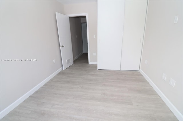 unfurnished bedroom featuring a closet and light wood-type flooring