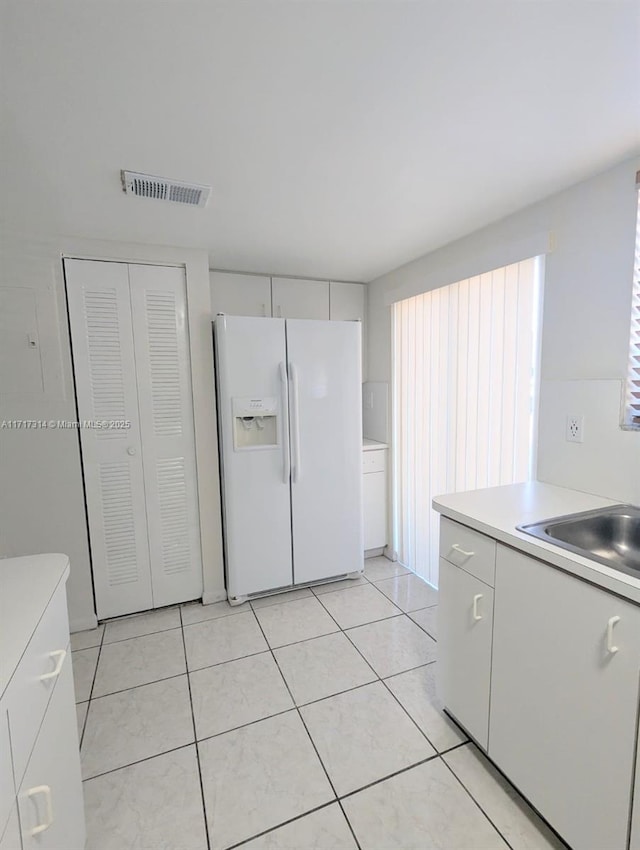 kitchen with white cabinetry, light tile patterned floors, and white refrigerator with ice dispenser