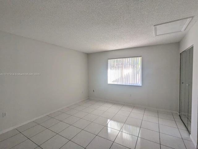 tiled empty room featuring a textured ceiling