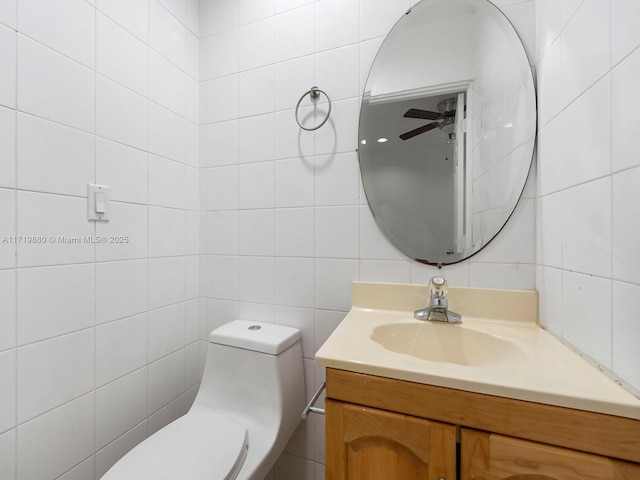 bathroom featuring toilet, tile walls, vanity, ceiling fan, and decorative backsplash