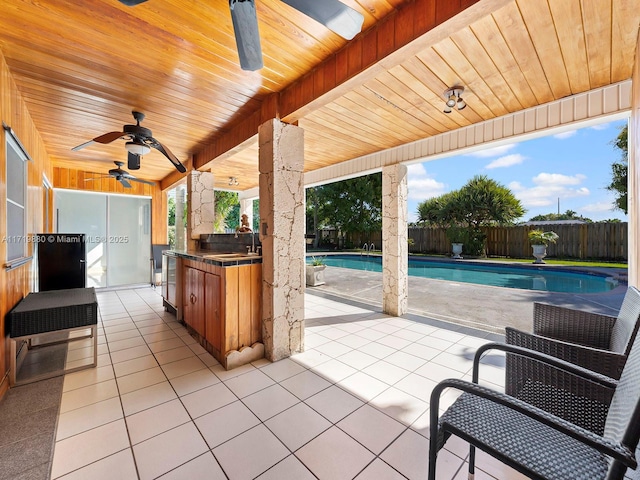 view of patio / terrace with a fenced in pool, ceiling fan, exterior kitchen, and a wet bar