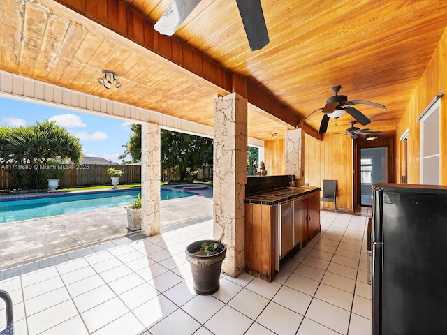 view of patio featuring ceiling fan, a fenced in pool, and an outdoor wet bar