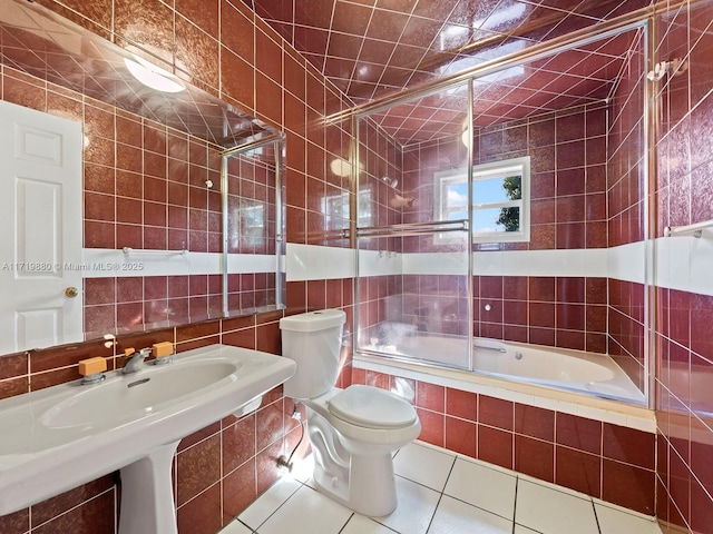 bathroom with bath / shower combo with glass door, tile walls, backsplash, tile patterned flooring, and toilet