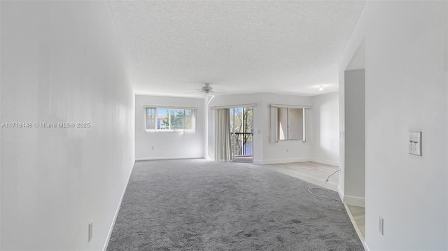 empty room featuring light carpet, ceiling fan, and a textured ceiling