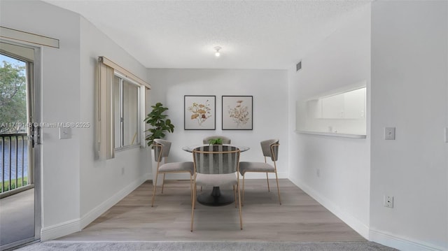 dining space featuring light hardwood / wood-style floors and a textured ceiling