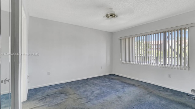 spare room featuring a textured ceiling and dark carpet