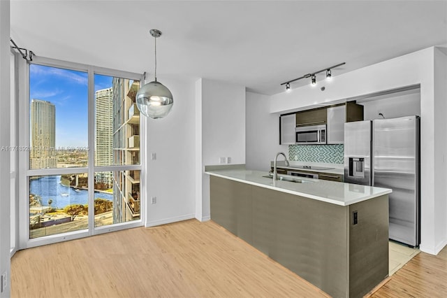 kitchen featuring sink, tasteful backsplash, decorative light fixtures, kitchen peninsula, and stainless steel appliances