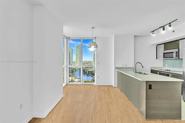 kitchen with backsplash, a water view, sink, hanging light fixtures, and a wall of windows