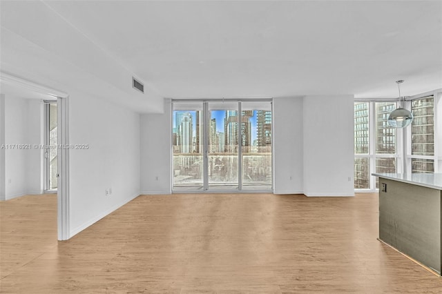 unfurnished living room with floor to ceiling windows and light hardwood / wood-style flooring