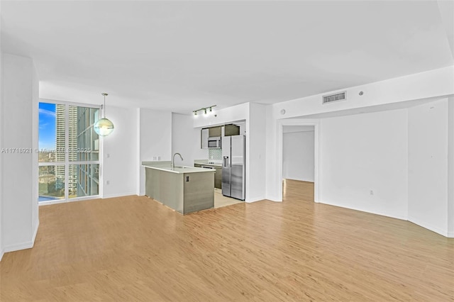 kitchen with sink, pendant lighting, light wood-type flooring, and stainless steel fridge with ice dispenser