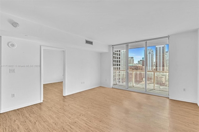 unfurnished room with a wall of windows and light wood-type flooring