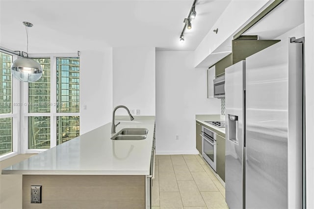 kitchen with sink, rail lighting, hanging light fixtures, light tile patterned floors, and appliances with stainless steel finishes